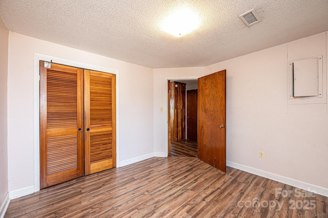 unfurnished bedroom featuring wood-type flooring, a closet, and a textured ceiling