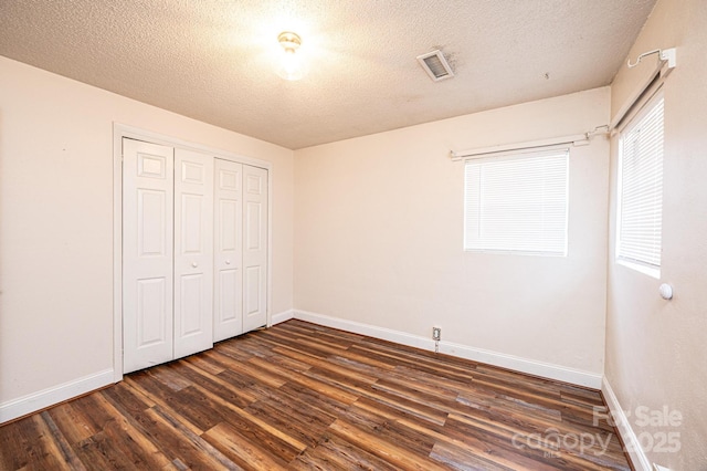 unfurnished bedroom with dark wood-type flooring, a closet, and a textured ceiling