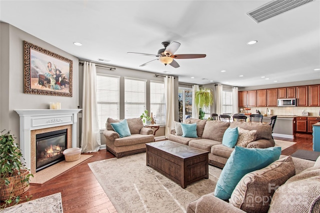 living room with ceiling fan, a fireplace, and light wood-type flooring