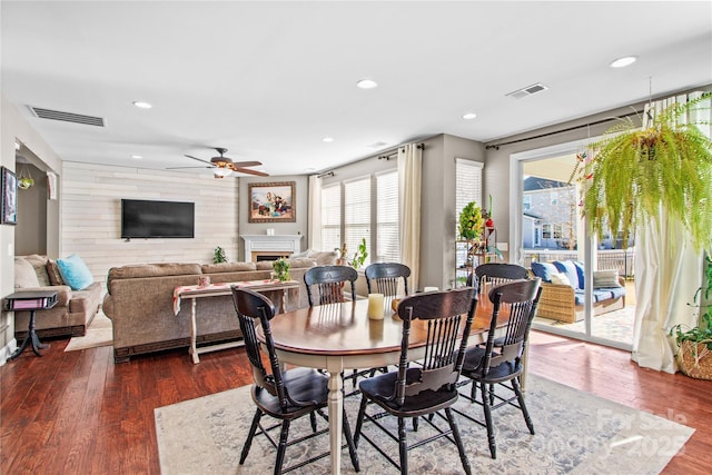 dining room with ceiling fan, wooden walls, and dark hardwood / wood-style flooring