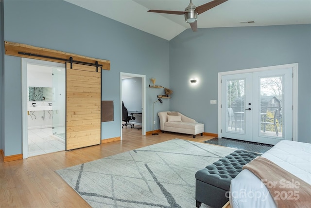 bedroom featuring lofted ceiling, access to exterior, hardwood / wood-style floors, french doors, and a barn door