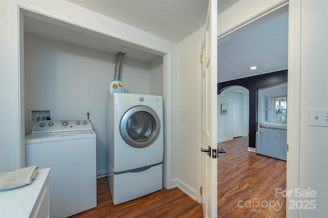 laundry room featuring dark wood-type flooring, washing machine and dryer, and a textured ceiling