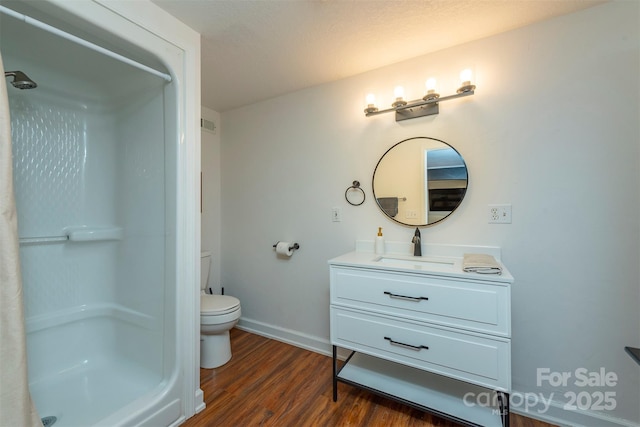 bathroom with hardwood / wood-style flooring, vanity, toilet, and walk in shower