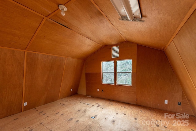 additional living space with lofted ceiling and wood walls