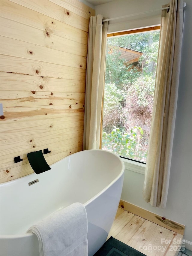 bathroom with hardwood / wood-style floors, a healthy amount of sunlight, and a washtub