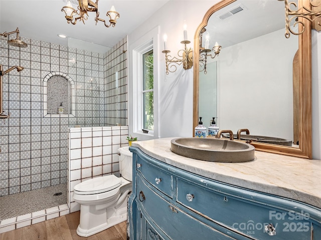 bathroom featuring tiled shower, toilet, a chandelier, vanity, and hardwood / wood-style flooring