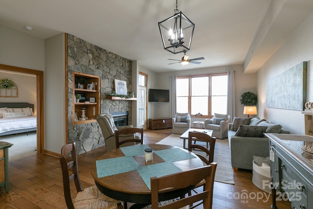 dining space featuring ceiling fan, a stone fireplace, and light hardwood / wood-style floors