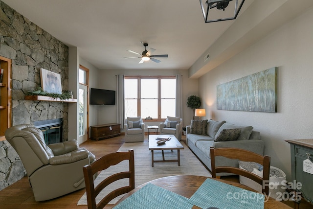 living room with ceiling fan, a fireplace, and light hardwood / wood-style flooring