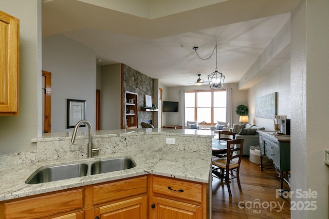 kitchen with sink, light stone counters, dark hardwood / wood-style flooring, kitchen peninsula, and ceiling fan