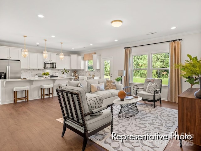 living room with crown molding, sink, and light hardwood / wood-style flooring