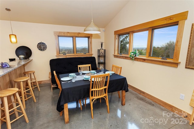 dining space with bar area, vaulted ceiling, and concrete floors