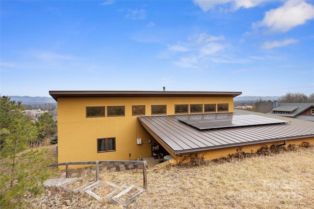 rear view of property with a mountain view and solar panels