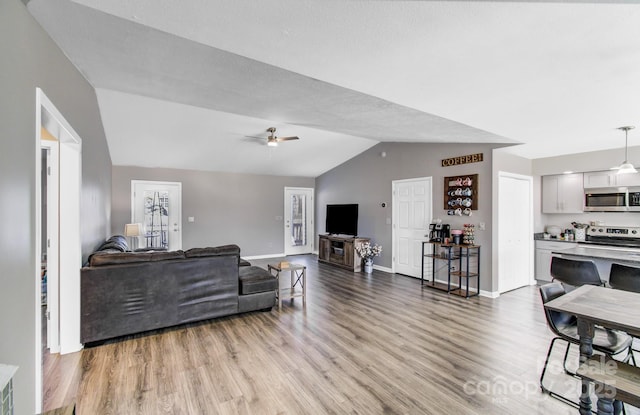 living room with ceiling fan, lofted ceiling, and light wood-type flooring