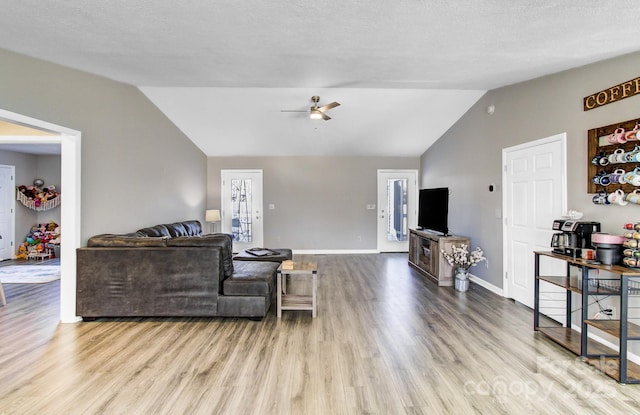 living room featuring vaulted ceiling, a textured ceiling, ceiling fan, and light hardwood / wood-style floors