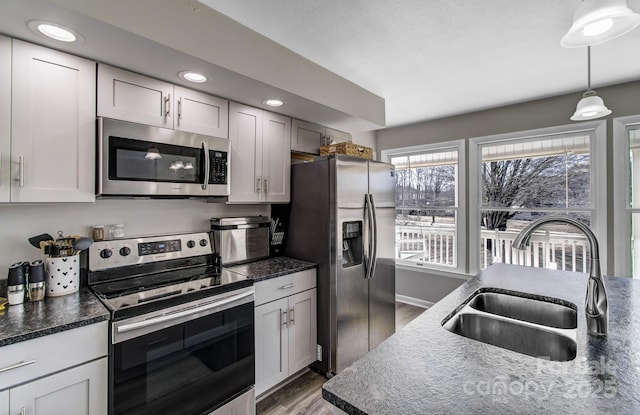 kitchen featuring sink, appliances with stainless steel finishes, pendant lighting, hardwood / wood-style floors, and white cabinets