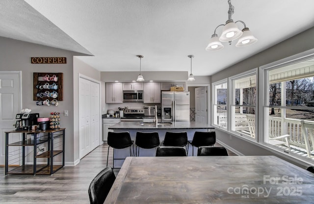 dining room featuring an inviting chandelier, sink, a textured ceiling, and light wood-type flooring