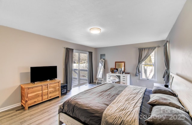 bedroom with multiple windows, access to exterior, and light hardwood / wood-style floors