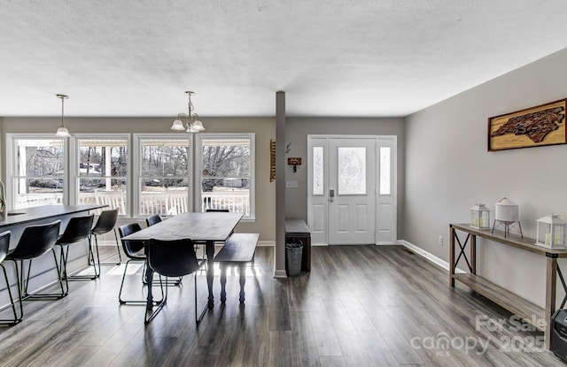 dining room featuring dark hardwood / wood-style flooring, a textured ceiling, and a notable chandelier