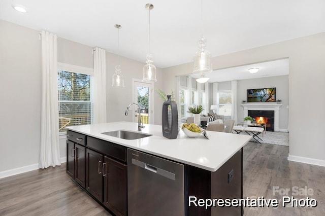 kitchen featuring pendant lighting, dishwasher, an island with sink, sink, and dark brown cabinets