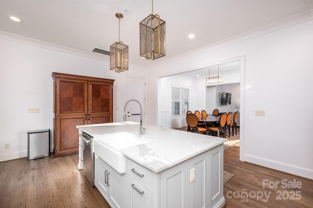 kitchen with a sink, white cabinets, hanging light fixtures, light stone countertops, and dishwasher