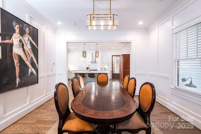 dining room with a notable chandelier, recessed lighting, light wood-style flooring, and a decorative wall