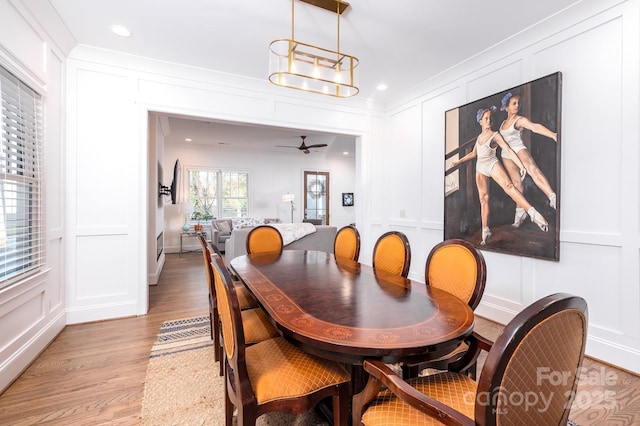 dining area with light wood-type flooring, ornamental molding, a decorative wall, and recessed lighting