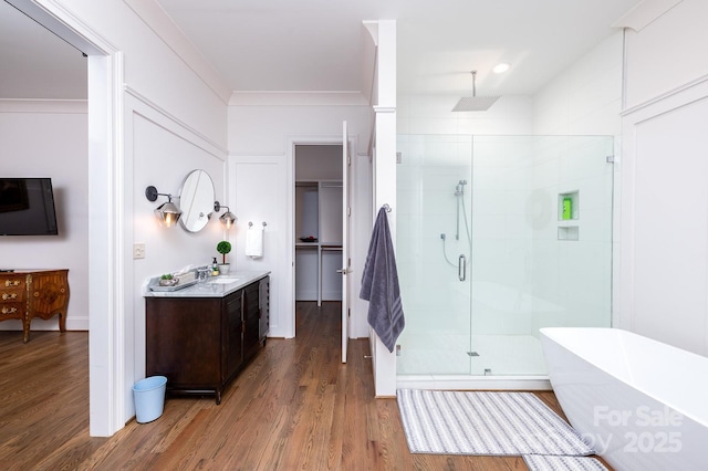 full bathroom with a freestanding tub, wood finished floors, vanity, ornamental molding, and a shower stall