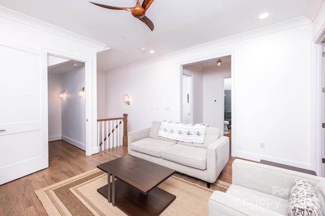 living room featuring light wood-style floors, baseboards, ornamental molding, and recessed lighting