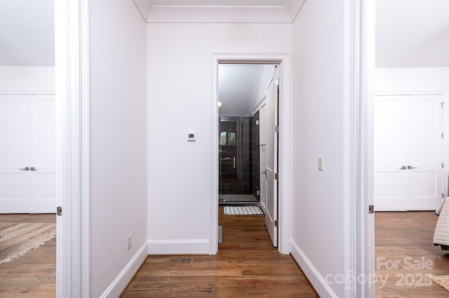 corridor featuring baseboards and wood finished floors