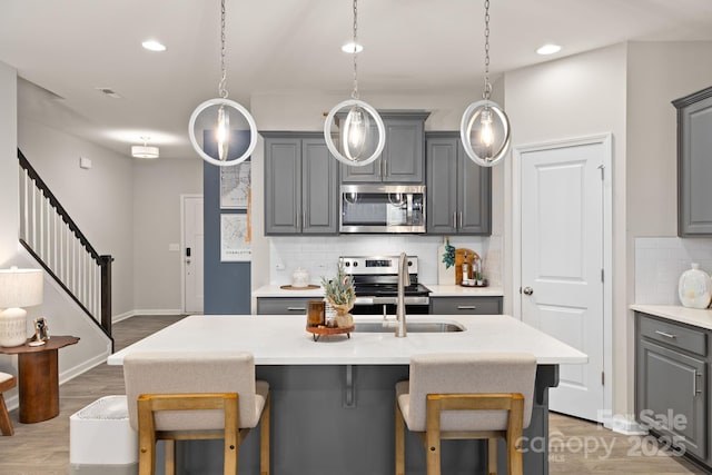 kitchen with gray cabinetry, hanging light fixtures, and stainless steel appliances