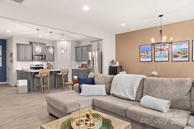 living room with sink, a chandelier, and light hardwood / wood-style flooring