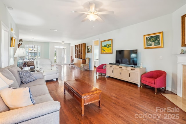 living room featuring a fireplace, ceiling fan with notable chandelier, and wood-type flooring