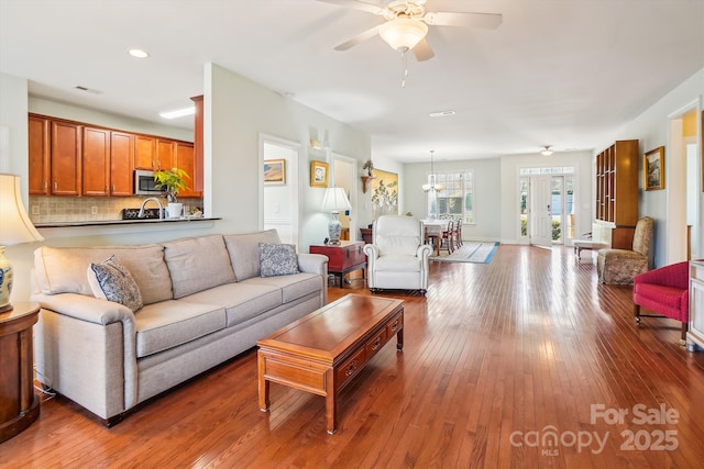 living room with hardwood / wood-style floors and ceiling fan with notable chandelier