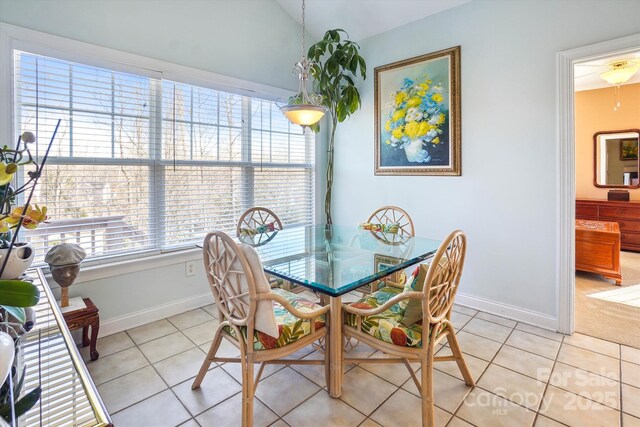 tiled dining space featuring vaulted ceiling