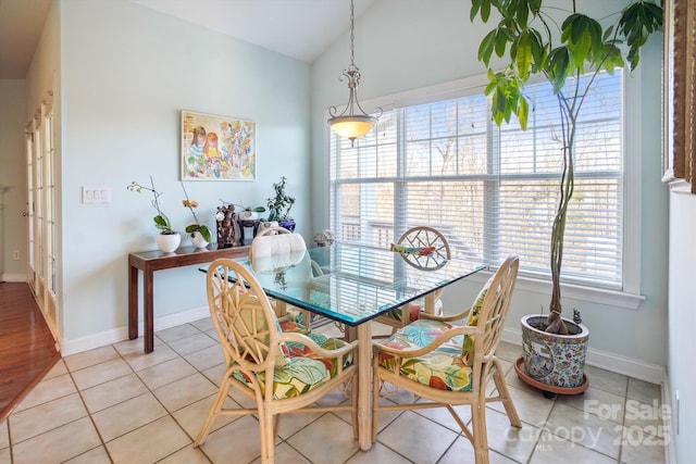 tiled dining space featuring vaulted ceiling