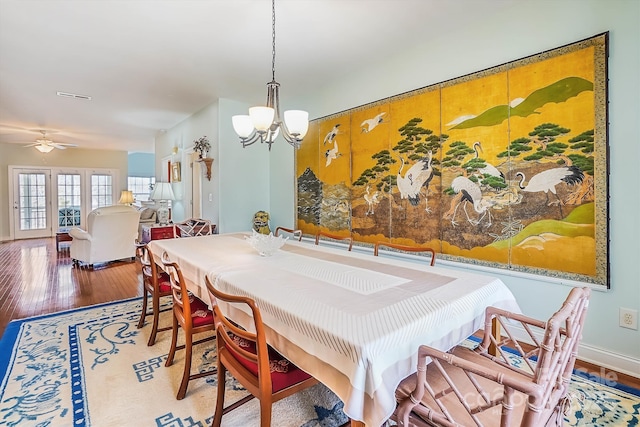 dining area with hardwood / wood-style flooring and ceiling fan with notable chandelier