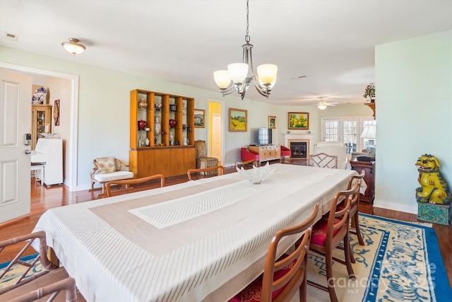 dining area featuring hardwood / wood-style flooring and ceiling fan with notable chandelier