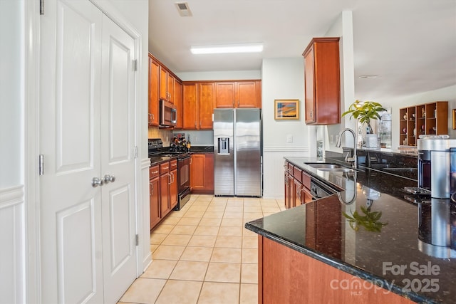 kitchen with dark stone countertops, sink, stainless steel appliances, and light tile patterned flooring