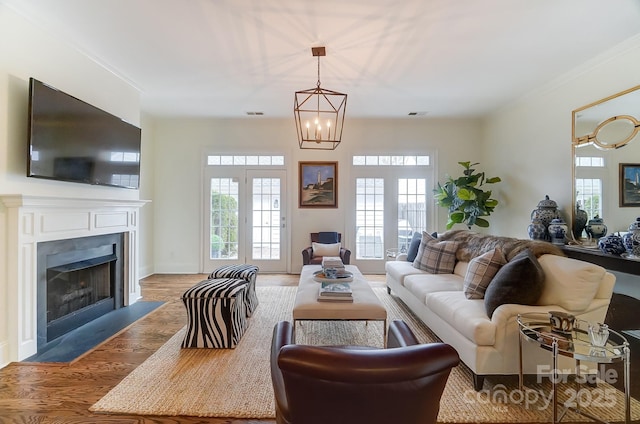 living room featuring an inviting chandelier, ornamental molding, and light wood-type flooring