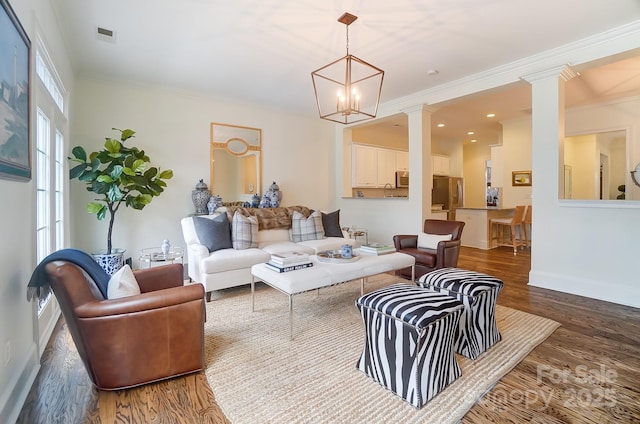 living room with decorative columns, crown molding, dark wood-type flooring, and a chandelier