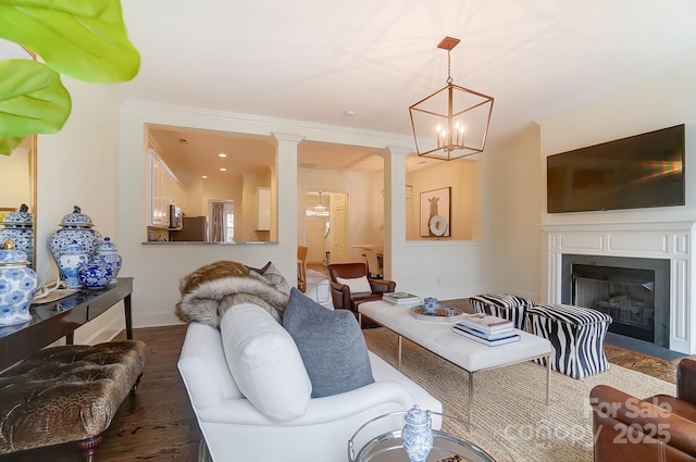 living room with dark hardwood / wood-style flooring, ornamental molding, decorative columns, and a chandelier