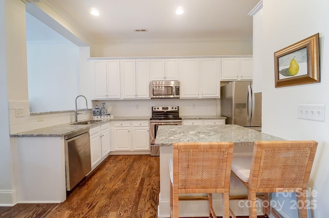 kitchen featuring appliances with stainless steel finishes, sink, white cabinets, light stone counters, and kitchen peninsula