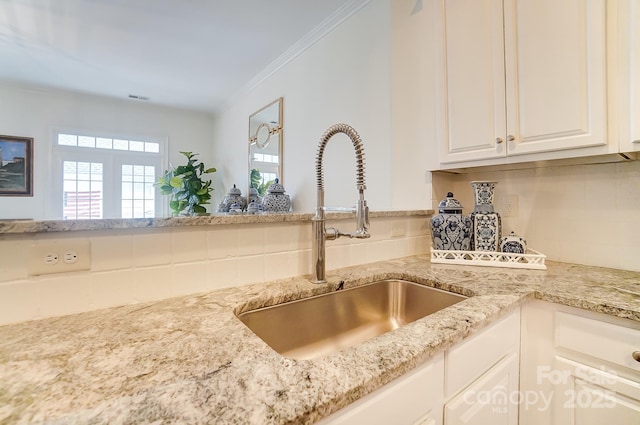 kitchen featuring sink, white cabinetry, ornamental molding, light stone countertops, and decorative backsplash