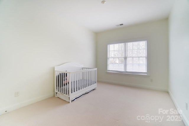 unfurnished bedroom featuring a nursery area and light carpet