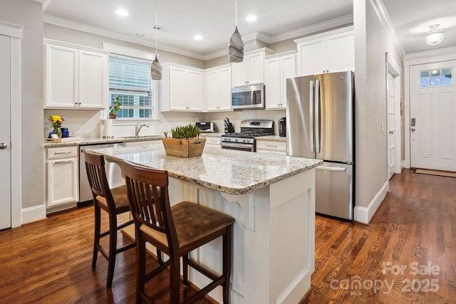 kitchen with appliances with stainless steel finishes, a center island, white cabinets, and decorative light fixtures