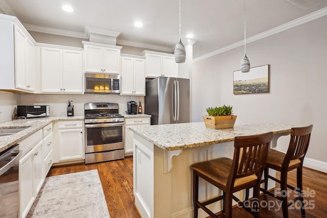 kitchen with hanging light fixtures, stainless steel appliances, and white cabinets