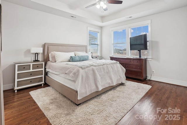 bedroom featuring ceiling fan, dark hardwood / wood-style floors, and a raised ceiling