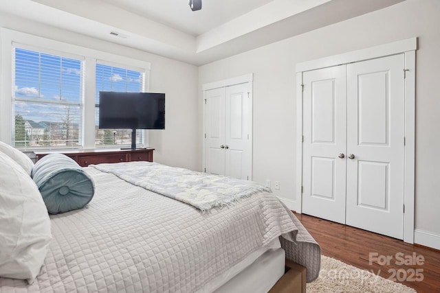 bedroom with multiple closets, ceiling fan, and hardwood / wood-style floors