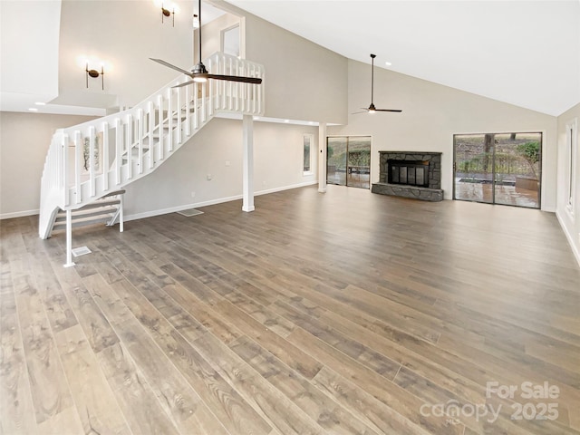 unfurnished living room featuring hardwood / wood-style flooring, a fireplace, high vaulted ceiling, and ceiling fan