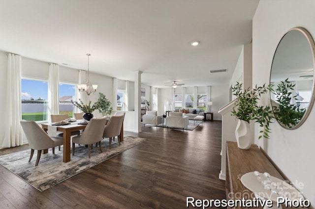 dining room featuring ceiling fan with notable chandelier, dark wood-type flooring, and a healthy amount of sunlight